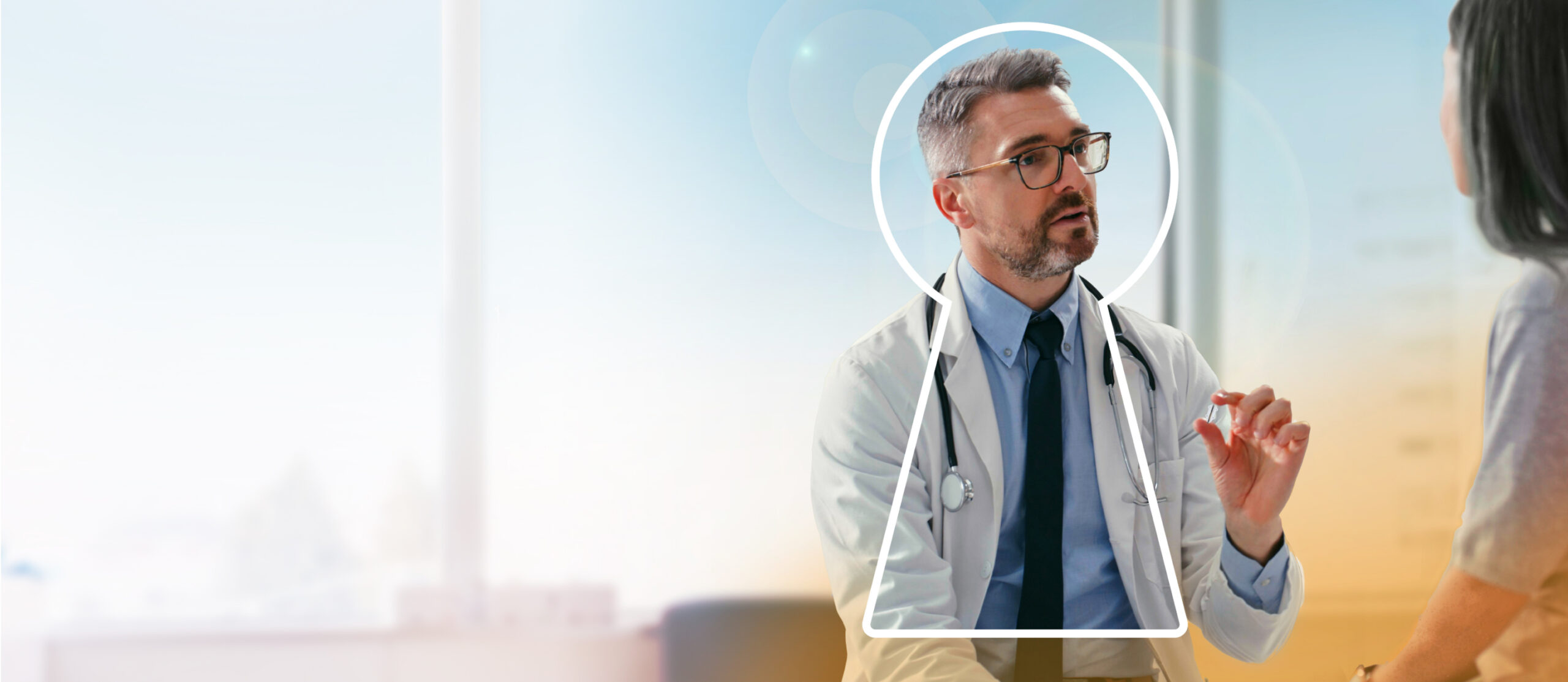 Male physician holding the Revi device between his fingers while talking to patient out of view.