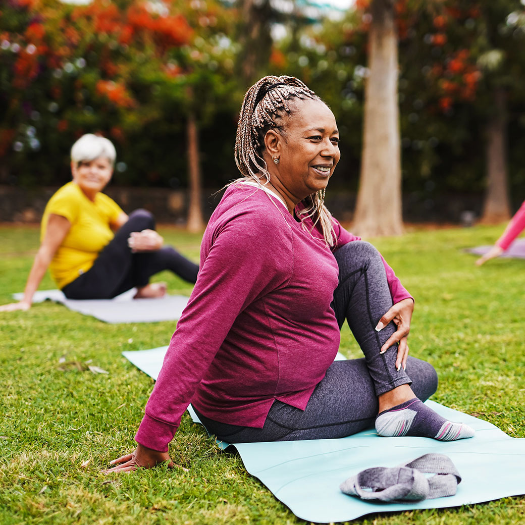 Two middle aged women doing yoga in the park.